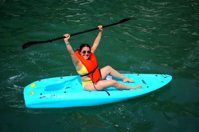 A guest paddling a kayak across green water