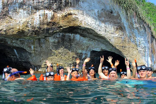 Snorkelers floating at the entrance of a rock arch