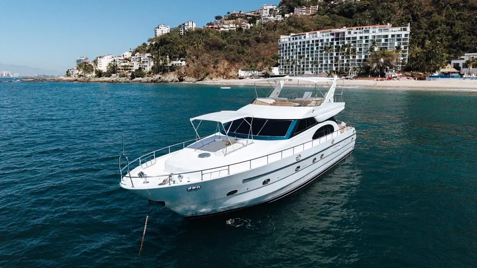 The VTech 65 luxury yacht on calm water beside a green hillside coastline